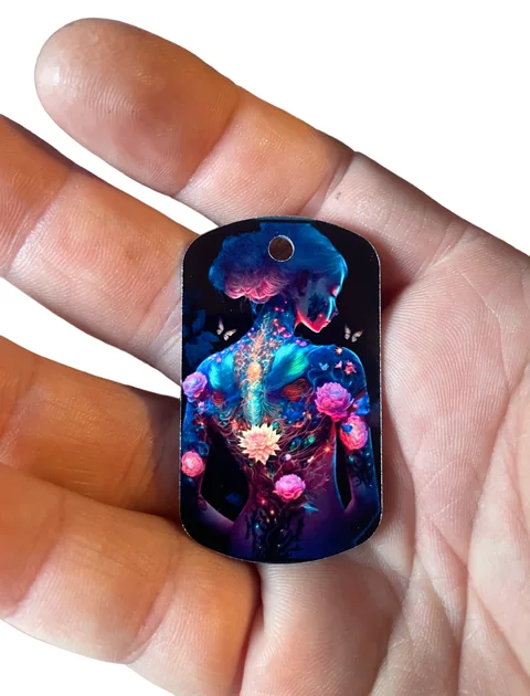 Ciondolo rettangolare con profilo illustrato e fiori blu e rosa, tenuto tra le dita