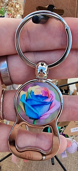 Portachiavi metallico con elemento trasparente e fiore azzurro, tenuto in mano