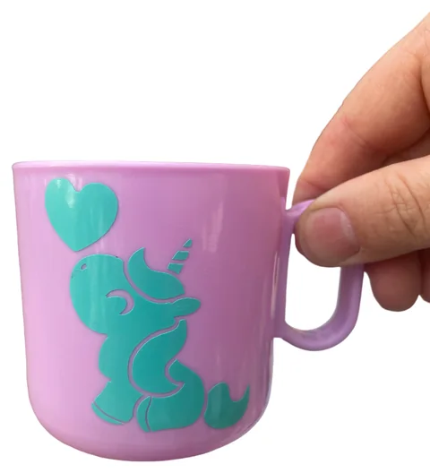 Tazza rosa con unicorno e cuore verde acqua, sostenuta dal manico